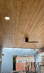 Modern ceiling with wood paneling, recessed light fixture, and ceiling fan in a room with blue walls